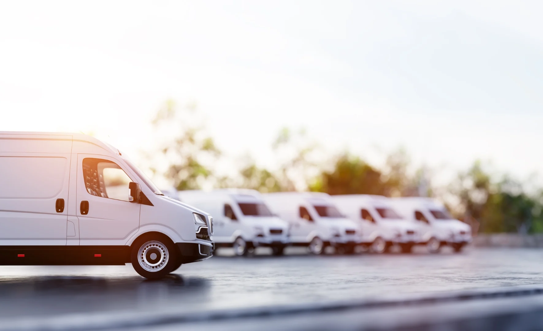 Fleet of white delivery vans parked outdoors at sunrise