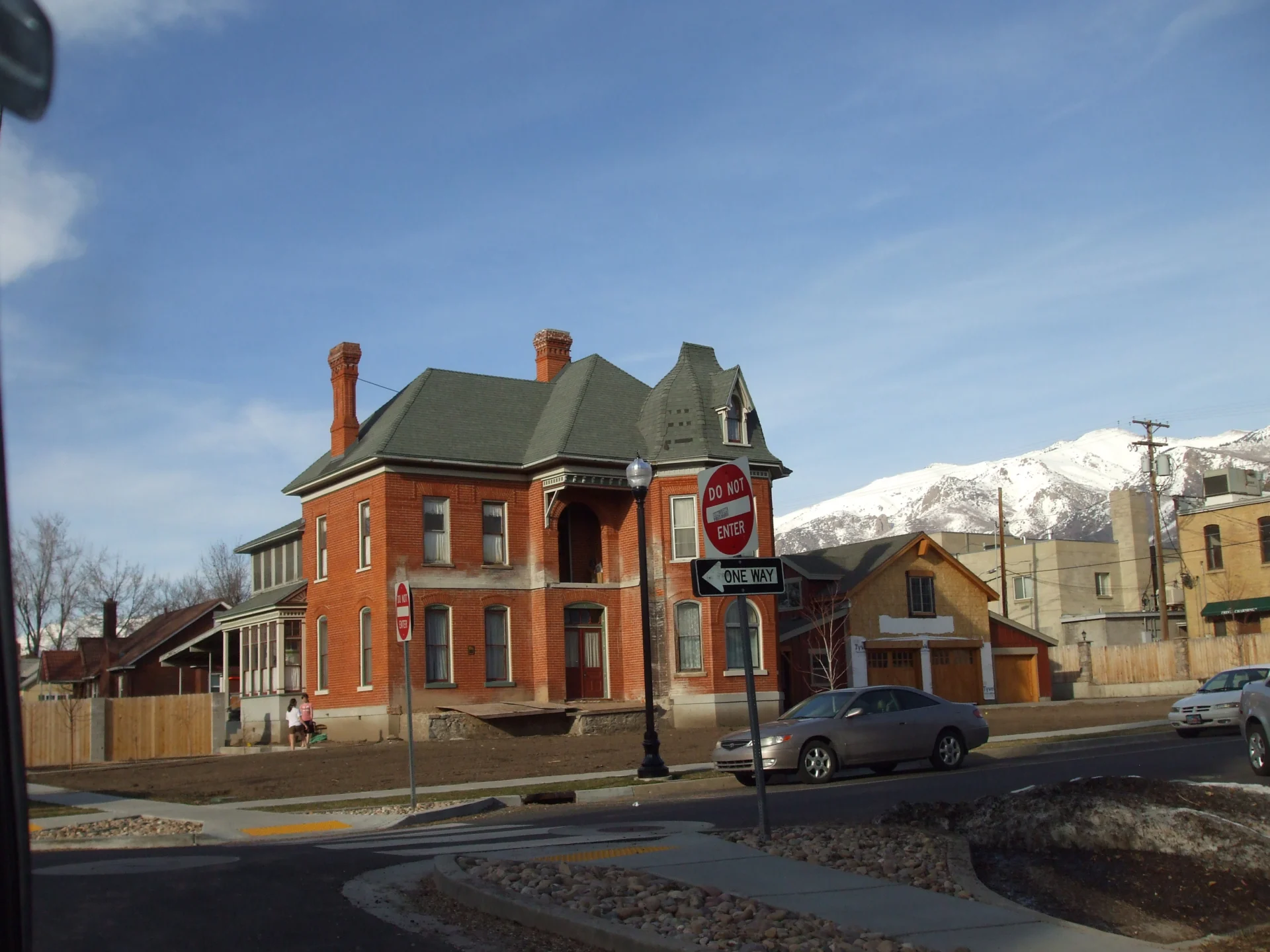 Victorian brick house with snow-capped mountains in the background.