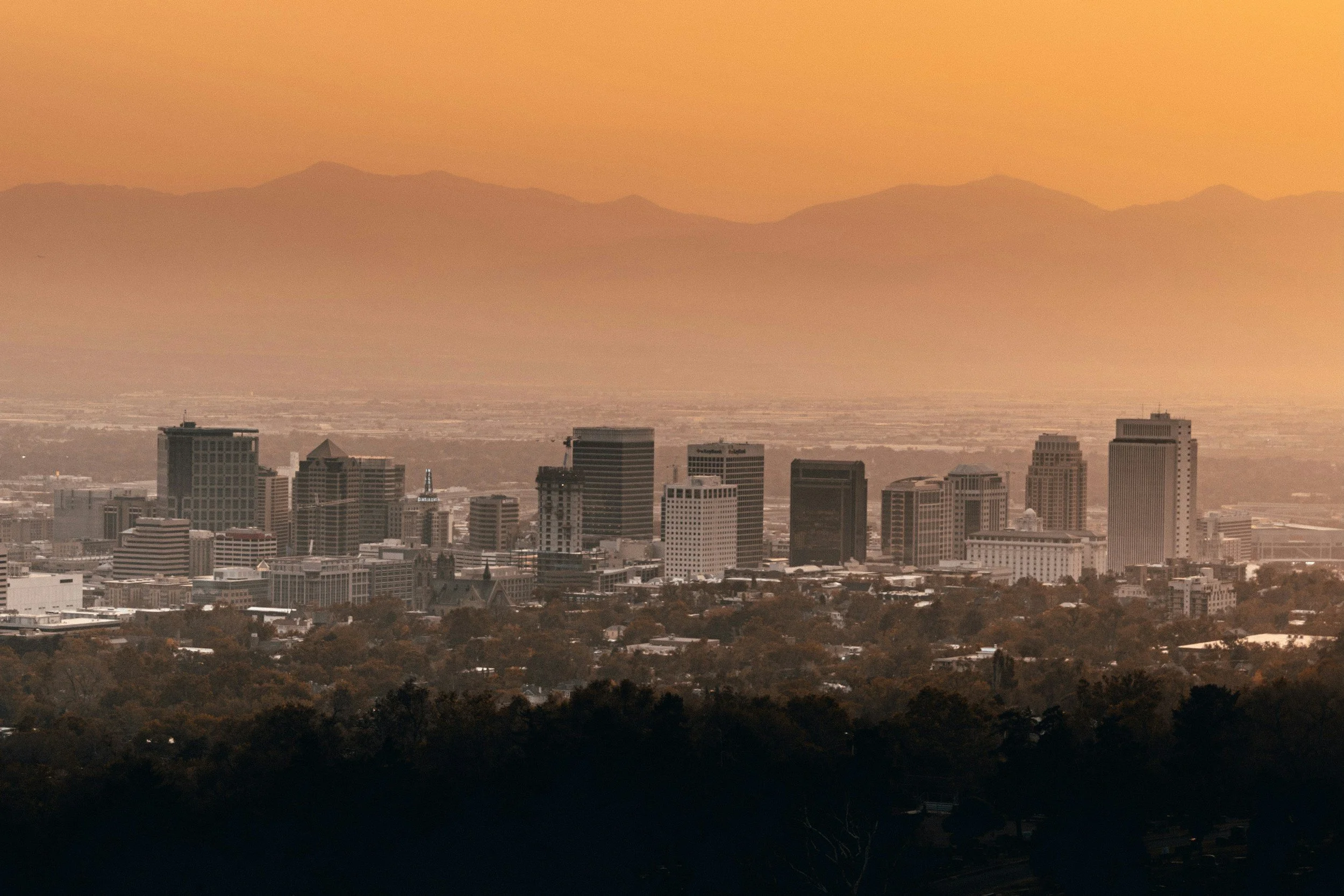 Salt Lake City skyline at sunset with mountains in the background.