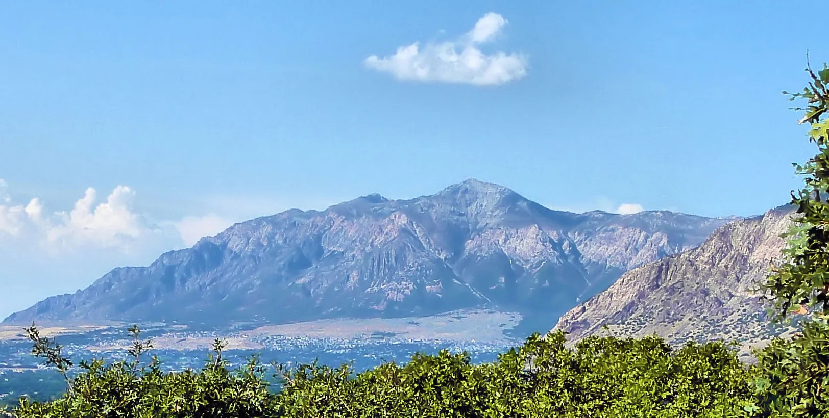 Majestic mountain range overlooking a valley town under a clear blue sky.