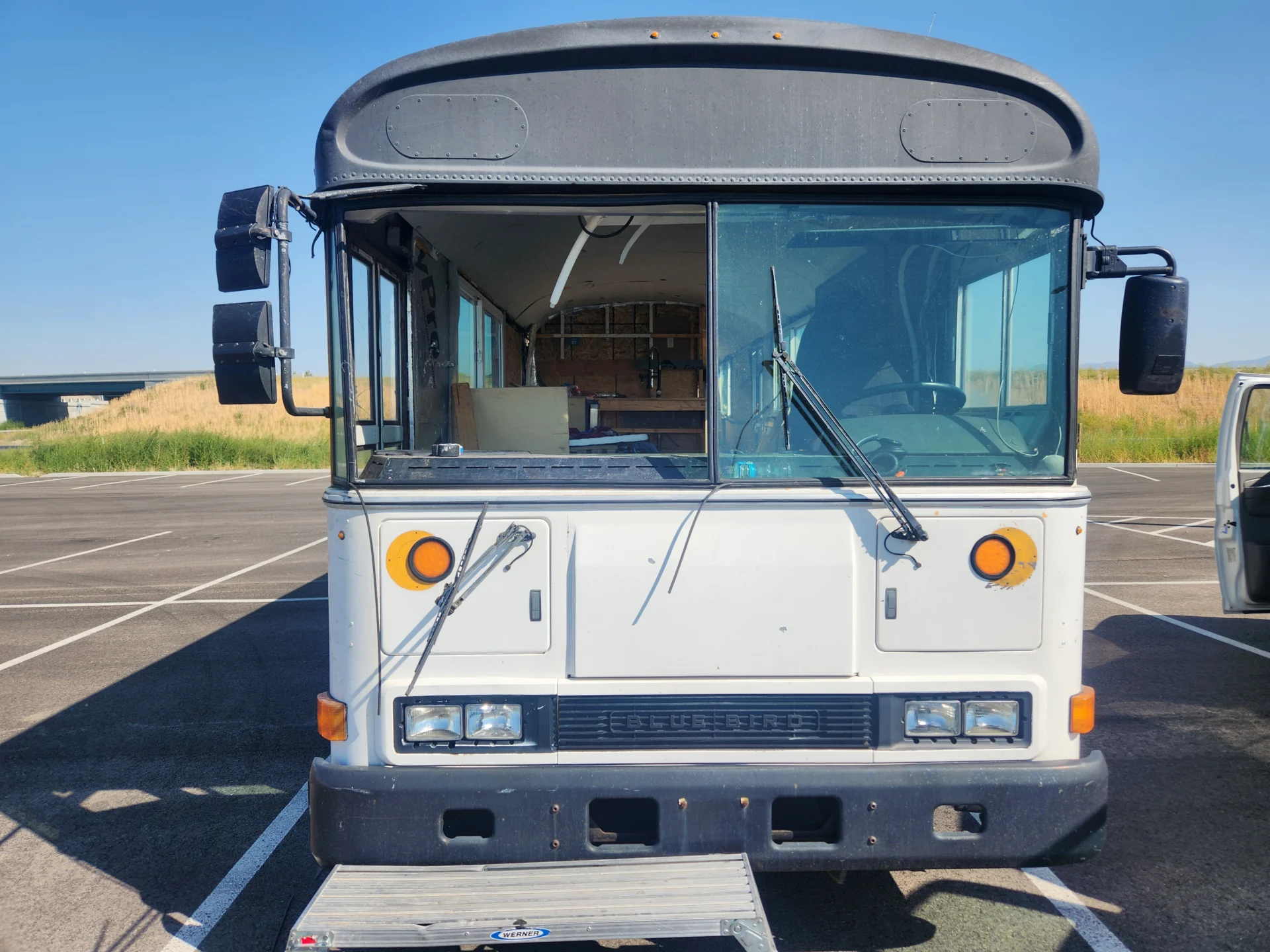 Front view of a white Blue Bird school bus being converted into a tiny home.